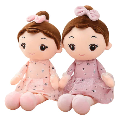 Two plush toys with brown hair and pink dresses on a wooden surface.